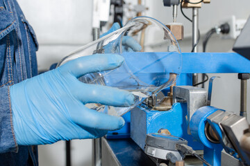 Industrial worker hands with blue latex gloves holding a glass container while pouring water