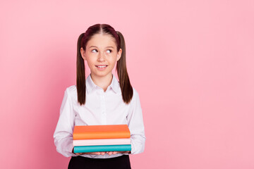 Photo of young happy small girl pupil look empty space hold hands textbooks isolated on pink color background