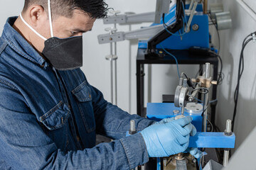 Close-up of Latin man using protective mask and blue latex gloves calibrating a geological testing machine