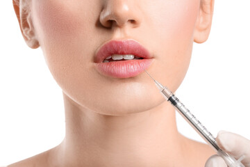 Obraz premium Young woman receiving filler injection in lips against white background, closeup