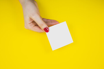 Blank white To Do List Sticker in woman hand. Close up of reminder note paper on the yellow background. Copy space. Minimalism, original and creative photo.