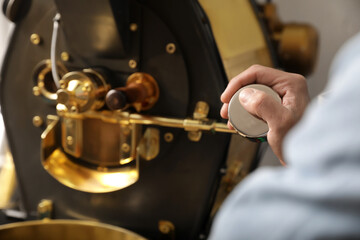 Senior man using modern coffee roaster, closeup