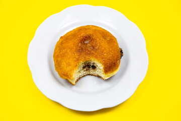 Bitten Donut with chocolate on plate. Delicious sweets temptation and desserts on a yellow...
