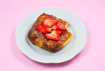 Bitten Puff pastry bun or roll. Cake with fresh strawberries. Delicious sweets temptation and desserts on a pink background. Minimalism, original and creative image. Beautiful food wallpaper.