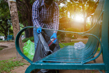 Volunteers wearing blue gloves pick up trash There are plastic water bottles, coffee mugs and other trash that people throw in the park. Ecology, environment and recycling concepts.