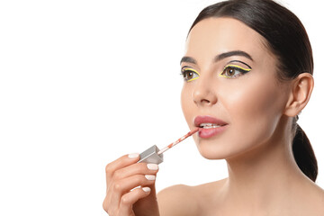 Fototapeta premium Beautiful young woman applying lipstick on white background