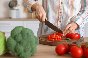 Woman cutting bell pepper in kitchen