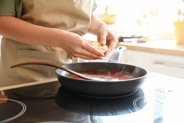 Woman preparing tomato sauce in kitchen