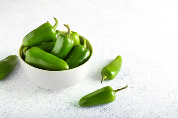 Bowl with green jalapeno peppers on light background, closeup