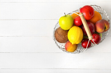 Basket with fresh fruits on light wooden background