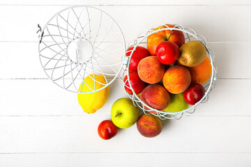 Basket with fresh fruits on light wooden background