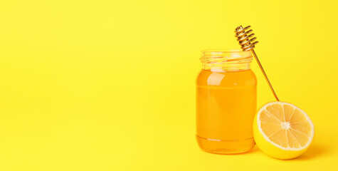Jar of honey with lemon on color background