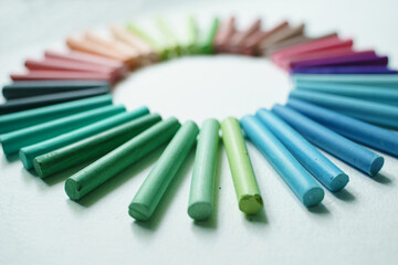 Crayons of multi-colored pastels are laid out in a circle close-up.