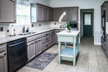 A renovated kitchen in an older home with painted gray cabinets, marble countertops, a small...