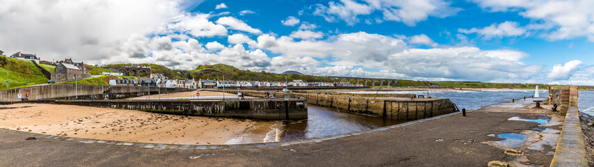 Fototapeta na wymiar A panorama view across the inner harbour towards the distant viaduct at the town of Cullen, Scotland on a summers day