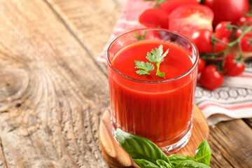Glass of tasty tomato juice on wooden background