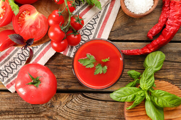 Glass of tasty tomato juice on wooden background