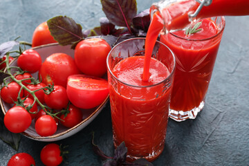 Glasses of tasty tomato juice on dark background