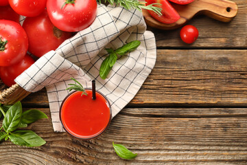 Glass of tasty tomato juice on wooden background