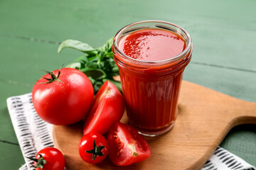 Glass of tasty tomato juice on color wooden background
