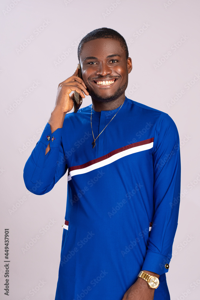 Wall mural handsome, happy young african man smiling while making a phone call