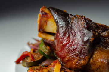 Bacon joint with bone served with grilled vegetables, red and yellow peppers, zucchini and red onion