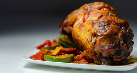 Bacon joint with bone served with grilled vegetables, red and yellow peppers, zucchini and red onion