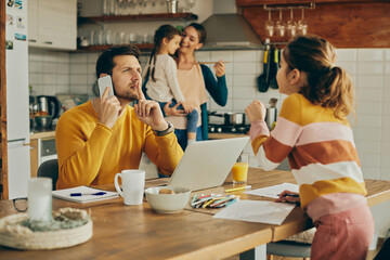 Working father silences his daughter while making a phone call from home.