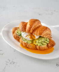 Croissant with guacamole and poached egg
