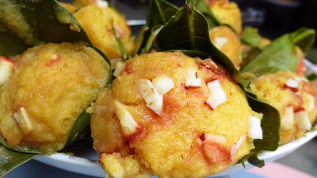 Traditional steamed ripe palmyra palm fruit cake wrapped with jackfruit leaves and sprinkled with coconut pieces. Steamed palmyra palm cake in closeup view. 4k video.