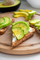 Fresh avocado toast with soft cheese, sliced avocado, salt and pepper on rye bread for breakfast or lunch. Clean eating., keto diet or vegaterian food concept.