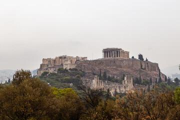 Acropolis hill (Parthenon, Propylaea, Temples, Odeon of Herodes Atticus) in summer. Athens ancient historical landmark in city center from Filopappou Hill on cloudy day