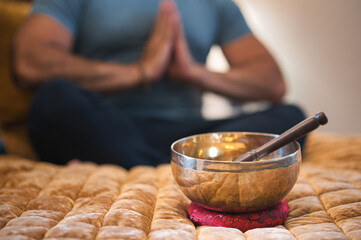 Obraz na płótnie Canvas Tibetan singing bowl with man praying in background