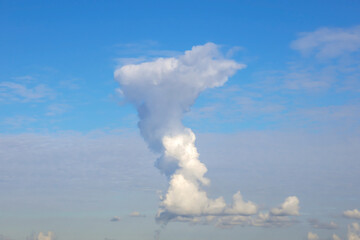 Naklejka na ściany i meble Background image: a large vertical cloud high in the blue sky