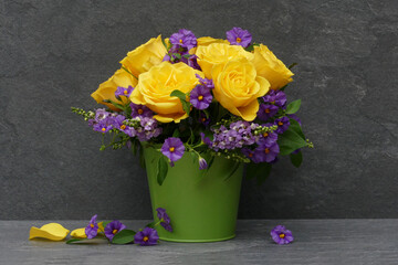 Gelber Rosenstrauß mit Petunien in einer Vase.