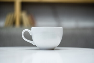 White ceramic mug with blurred background and white table
