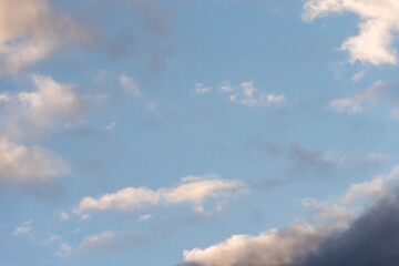 Beautiful fluffy clouds in the evening sky. The sunlight gives a side light on the clouds. Clouds before rain.