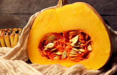 a large pumpkin in the section of a selective focus on a wooden background and baking dough from the back.