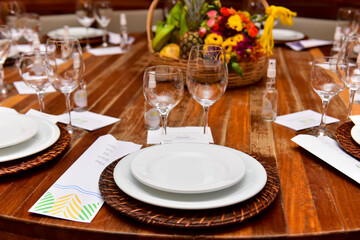 table set for dinner with white plates, glass glasses and alcohol to sanitize hands, ornamental flowers