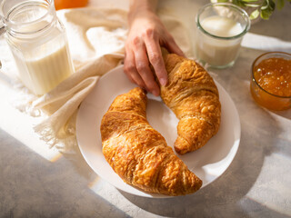 On a white silk tablecloth, a traditional classic breakfast - croissants, milk, jam. Beautiful composition. Low angle view. Cookbook, restaurant, hotel, advertisement.