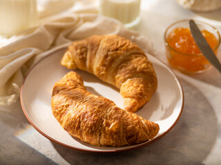 Croissants, jam, milk. Close-up. Focusing on the foreground. Tasty breakfast. White silk tablecloth. Restaurant, hotel and advertising business. Home kitchen. There is no one in the photo.