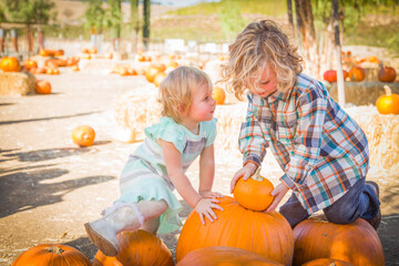 Sweet Little Boy Plays with His Baby Sister in a Rustic Ranch Setting at the Pumpkin Patch.