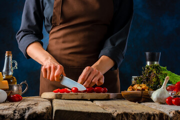 The chef prepares Caesar salad from the ingredients that are on the table. Dark background. Bright colors of ingredients. Close-up. High angle view. Home interior. Lots of ingredients.
