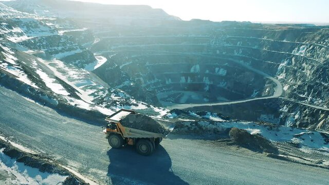 A truck with ore is moving along the open-pit slopes