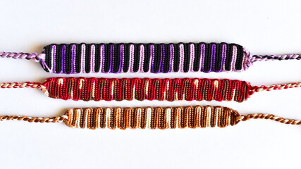 Woven DIY friendship bracelets handmade of embroidery bright thread with knots on white background.