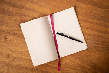 black pencil on recycled paper notebook with plant material on wooden desk