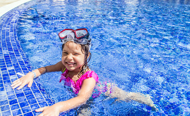 Niña Pequeña en la piscina sonriendo con sus lentes de snorkel 
