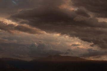 Dramatic sunset in the mountains. View of the Andes mountain range and cloudy sky with beautiful nightfall colors.