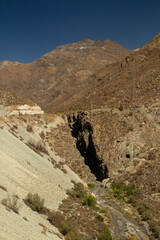 The arid mountains in summer. View of river flowing across the the gorge, sand and rock formations in the Andes cordillera. 