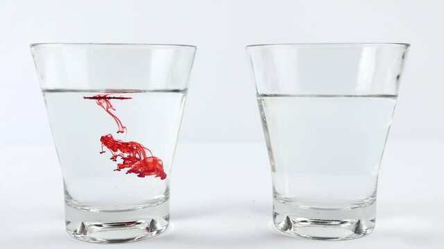 Pour red food coloring into a glass of warm water on the left and vinegar on the right. Diffusion science concept